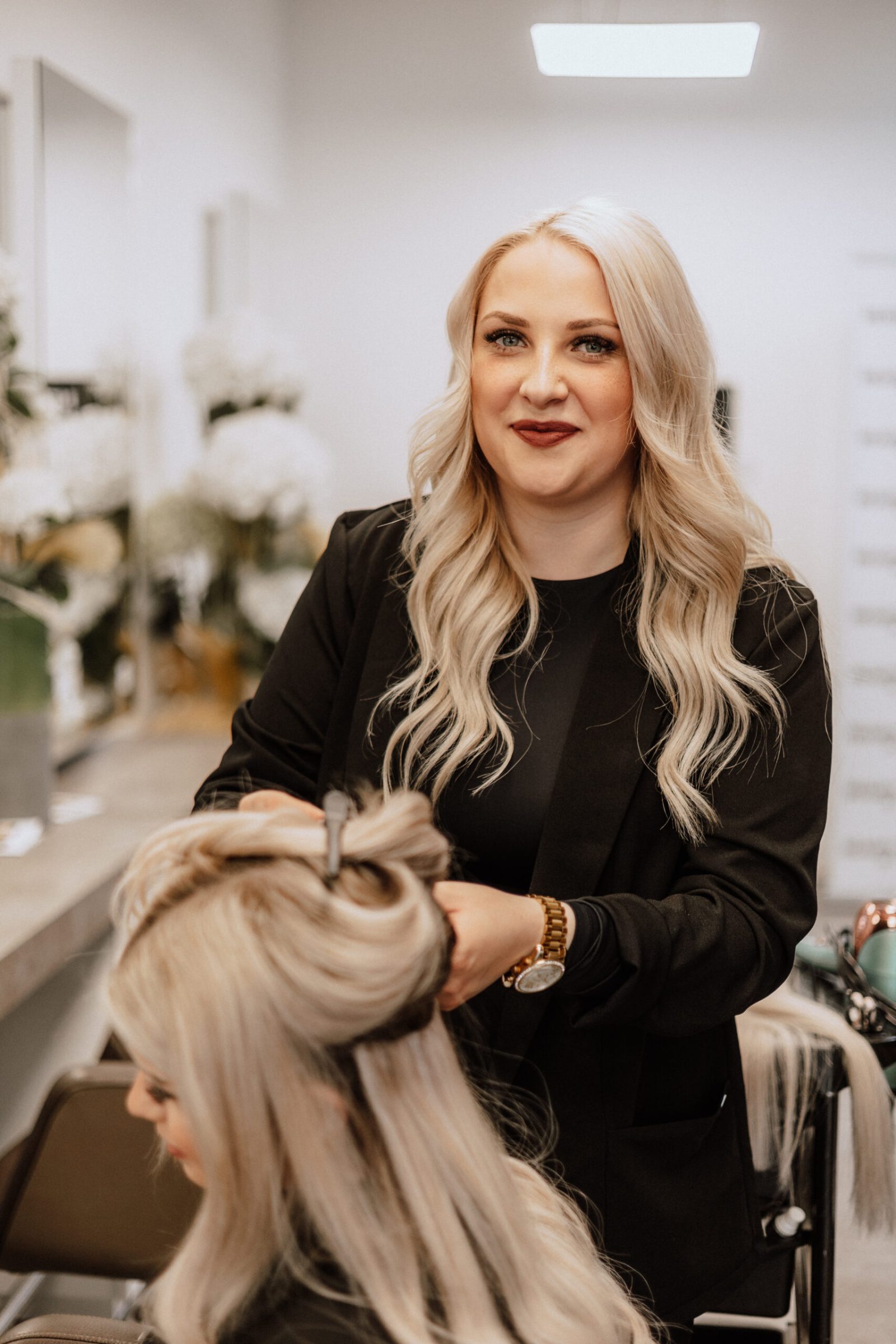 Stylistin beim Styling langer, gewellter Haare